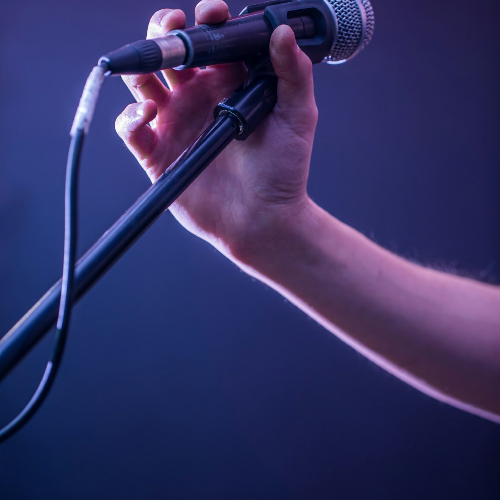 hand with microphone on a black background, the music concept, beautiful lighting on the stage